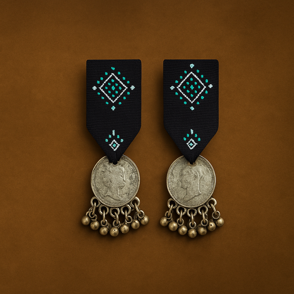 Pair of Cloth earrings with Indigo Blue Studs and Gujrati kutchi decorative elements and Silver coins on a vintage brown background