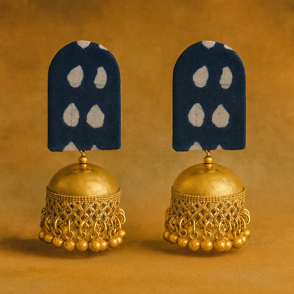 Pair of gold jhumka earrings with blue and white stone-studded pendants on a brown background