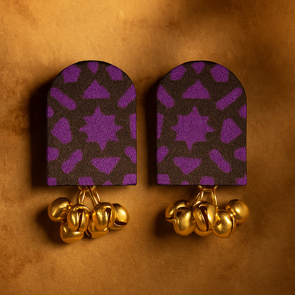 Pair of fabric earrings with purple patterned backs and gold accents on a brown background