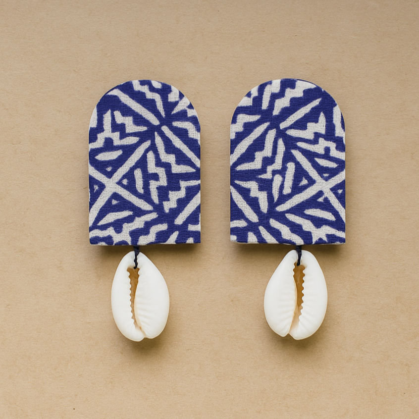 Pair of Cloth earrings with blue and white patterned indigo and cowrie shells on a beige background