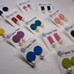 Colorful assorted fabric and pearl earrings on cards with 'Organic Vibes' branding on a white surface.