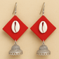 Fabric Earrings with red geometric pendants, cowrie shells, and silver jhumkas on a beige background