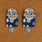 Pair of silver elephant earrings with blue polka dot fabric on a brown background