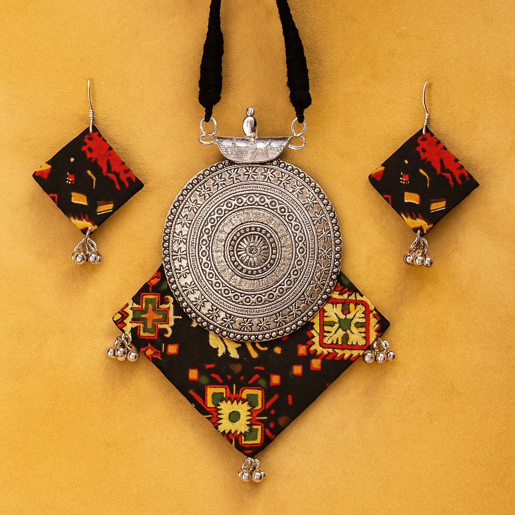 Antique Gujrati silver pendant with colorful fabric and earrings on a yellow background