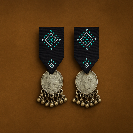Pair of Cloth earrings with Indigo Blue Studs and  Gujrati kutchi decorative elements and Silver coins  on a  vintage brown background