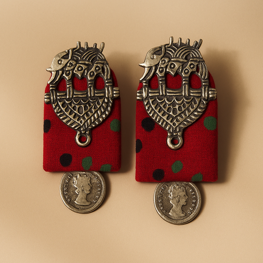 Pair of  Red Cloth earrings with red fabric backing and Antique silver metalwork on a beige background