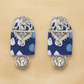 Pair of hand crafted earrings with indian silver  elephant decorative tops on Blue indigo fabric and silver coin-like bottoms on a beige background