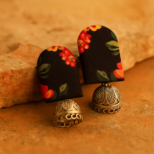 Pair of CLOTH earrings with floral design on black background and silver base on brown surface