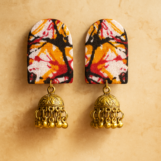 Pair of  FABRIC earrings with iKAT BENGALI design and gold jhumka details on a beige background
